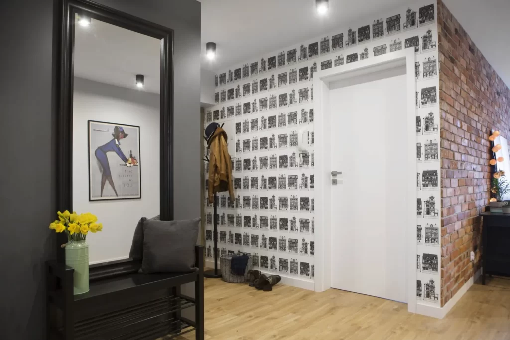 Nowoczesny korytarz ze wzorzystą tapetą, ścianą z cegły i ozdobnym lustrem.