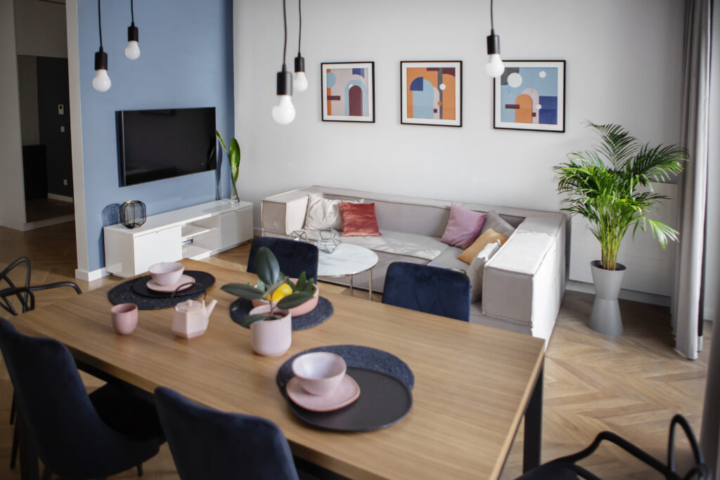 Nowoczesny salon z jadalnią, kanapą, TV i grafiką ścienną.